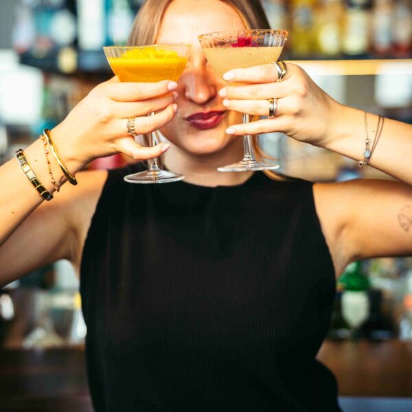 a woman holding two cocktails in front of her eyes