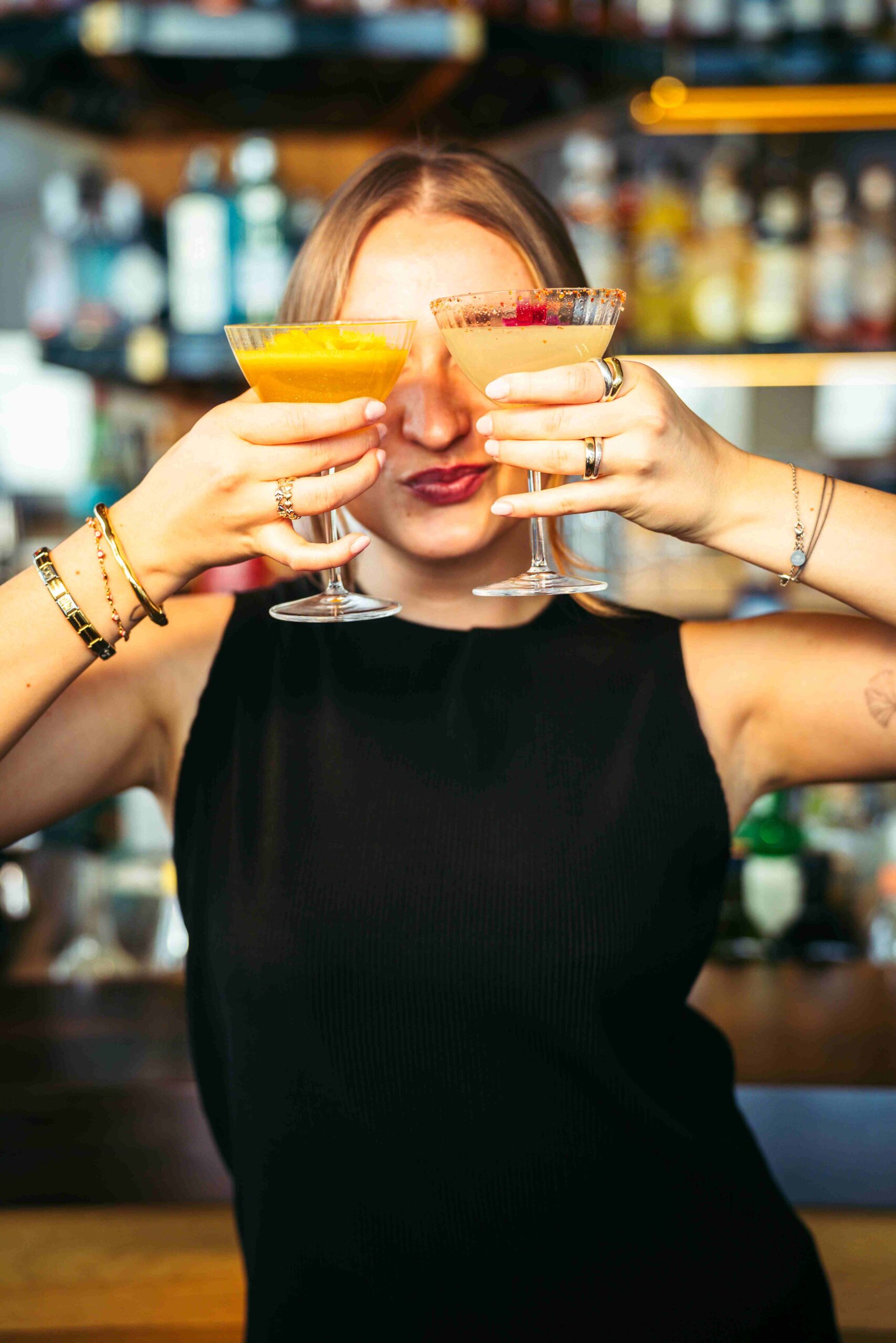 a woman holding two cocktails in front of her eyes